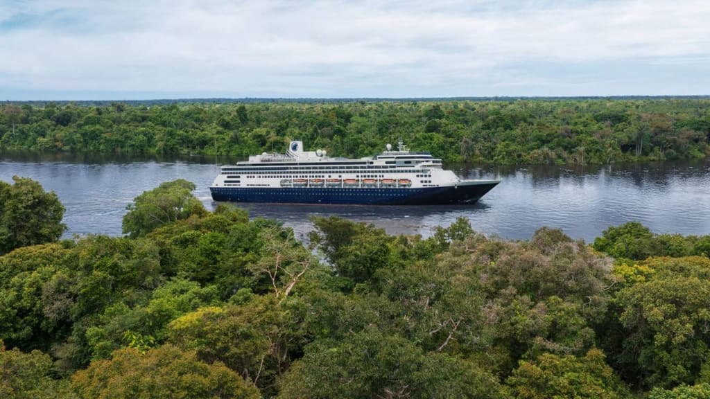 Volendam de Holland America Line navegando junto a una costa boscosa